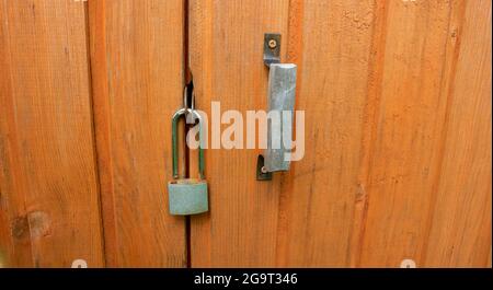 Une porte en bois marron déverrouillée avec un petit cadenas. Banque D'Images