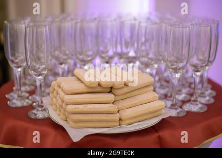 Table de réception pour événements ou mariages avec flûtes vides pour champagne ou boissons pétillées et biscuits éponge pour les ladyfinger, préparés pour les invités Banque D'Images