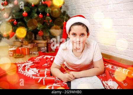 Garçon écrivant une lettre au Père Noël à la maison. Enfant écrivant la lettre Santa Banque D'Images