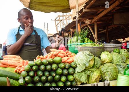 Photo de stock de l'épicerie africaine masculine avec un tablier, étonné comme il se tient et fixe à son téléphone Banque D'Images