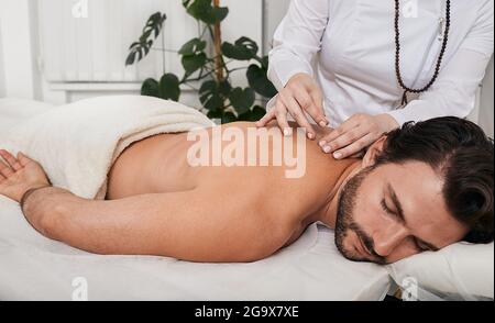 Médecine alternative, réflexologie. Traitement des douleurs dorsales et de l'oppression avec des aiguilles d'acupuncture pour un patient mâle, médecine chinoise traditionnelle Banque D'Images