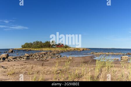 Un paysage côtier pittoresque sur la mer Baltique avec un petit cottage rouge sur une île derrière une plage de sable sous un ciel bleu Banque D'Images