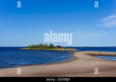 Un paysage côtier pittoresque sur la mer Baltique avec un petit cottage rouge sur une île derrière une plage de sable sous un ciel bleu Banque D'Images