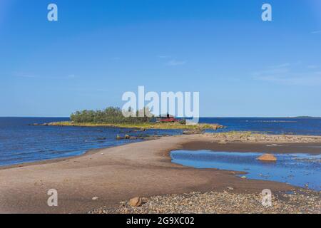 Un paysage côtier pittoresque sur la mer Baltique avec un petit cottage rouge sur une île derrière une plage de sable sous un ciel bleu Banque D'Images