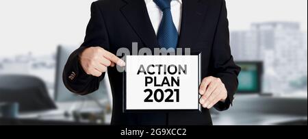 Homme d'affaires tient un panneau et pointe son doigt sur le message plan d'action 2021. Concept de plan d'action d'entreprise. Banque D'Images