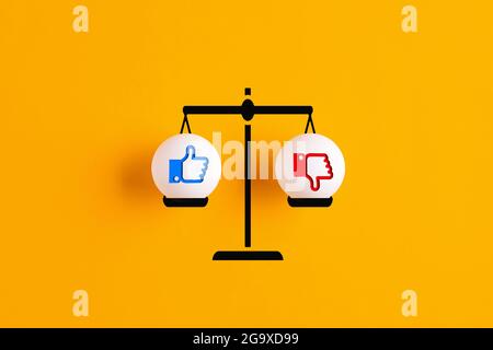 Les icônes like et dislike sont en équilibre sur une échelle avec un arrière-plan jaune. Concept de compatibilité avec les médias sociaux. Banque D'Images