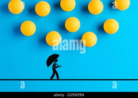 Les balles de tennis de table conçues comme des gouttes de pluie tombent sur l'icône d'un homme marchant avec un parapluie. Catastrophe, malchance, accident, risque ou danger concep Banque D'Images