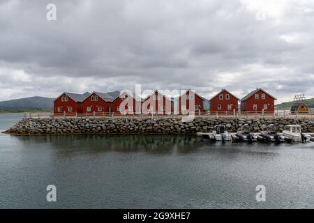 Skreda, Norvège - 20 juillet 2021 : maisons en bois rouge coloré sur le front de mer dans les îles Lofoten de Norvège avec des bateaux au quai dans le foregroun Banque D'Images