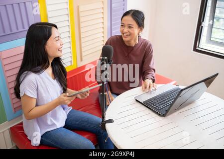 deux filles rient en discutant sur un podcast à l'aide d'un ordinateur portable Banque D'Images