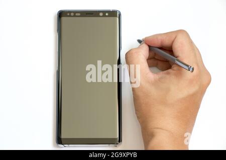 BANGKOK, THAÏLANDE - 23 décembre 2017 : homme d'affaires tient le stylet pour écrire à Samsung Galaxy Note 8 sur fond blanc. C'est le fleuron smartph Banque D'Images