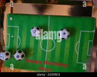 Gâteau d'anniversaire sportif amusant et charmant. Design avec le terrain de football. Chaussures, bâtiments, journée sportive. Gâteau, crème. Champ vert. Gâteau d'anniversaire pour un sport Banque D'Images