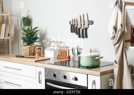Ustensiles de cuisine sur le comptoir et cuisinière près du mur lumineux Banque D'Images