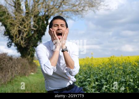 Homme debout dans un champ avec ses mains sur son visage criant, France Banque D'Images