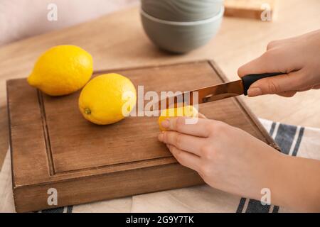 Femme coupant le citron dans la cuisine, gros plan Banque D'Images
