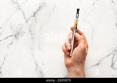 Main mâle avec cigarette électronique sur fond blanc Banque D'Images