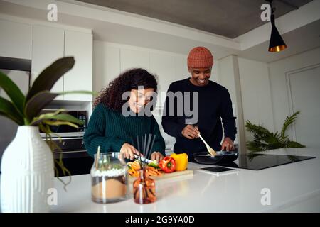 Un jeune couple de race mixte cuisant de la nourriture dans la cuisine à la maison. Couple préparant la nourriture. Photo de haute qualité Banque D'Images