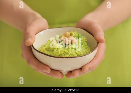 Femme au houmous aux pois verts savoureux dans un bol, en gros plan Banque D'Images