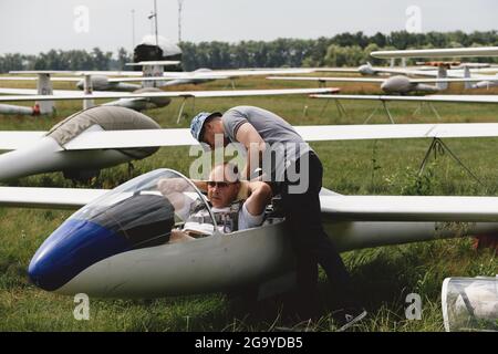 Un club qui s'évolte, prêt pour le vol à bord d'un avion de planeur. Petit sport d'aviation. Deux personnes vérifient le tableau de bord de l'habitacle d'un avion d'époque Banque D'Images