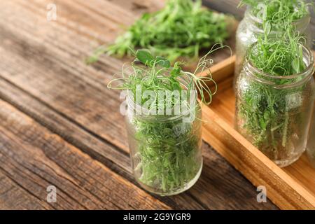 Pots en verre avec micro-vert frais sur fond en bois Banque D'Images