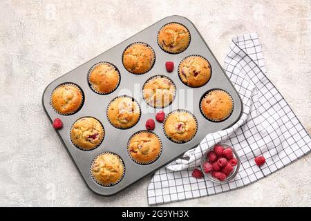 Moule à pâtisserie avec muffins savoureux à la framboise sur fond clair Banque D'Images