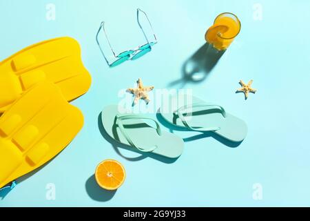 Tongs, lunettes de soleil, palmes et verre de jus sur fond coloré Banque D'Images