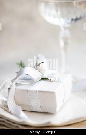 Cadeau de noël sur une serviette à côté d'un coupé à champagne sur une table Banque D'Images