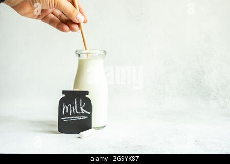 Femme remuant une bouteille de lait vintage à côté d'un tableau noir avec le mot lait Banque D'Images