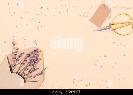 Composition plate de fleurs de lavande et de ciseaux sur table beige avec espace vide au centre. Banque D'Images
