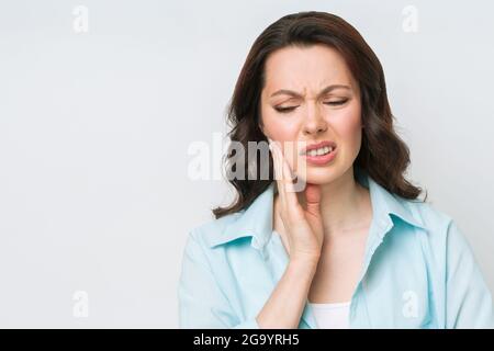 Jeune femme souffrant de fortes douleurs dentaires, touchant la joue avec la main. Concept de dentisterie Banque D'Images