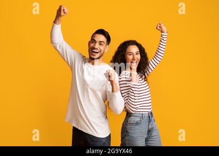 Grande chance. Un couple arabe débordant de joie élève les poings et s'exclame avec enthousiasme Banque D'Images