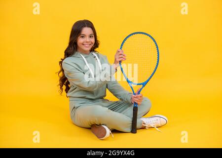 enfant dans les vêtements de sport tenir raquette. enfant avec raquette. jeune fille se détendre après l'entraînement sportif. Banque D'Images