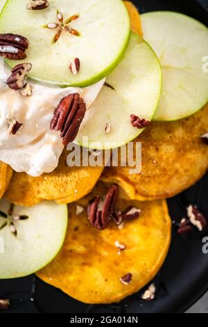 Crêpes à la citrouille fraîchement préparées avec pommes vertes sur une assiette de service noire. Banque D'Images