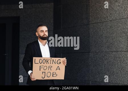 Un homme d'affaires mécontent a perdu du travail à la recherche d'un bon d'emploi, se tenant près du centre d'affaires et de l'espace libre Banque D'Images