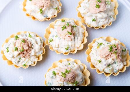 Tartelettes farcies au foie de morue, au caviar de morue, au concombre et aux microverts. Hors-d'œuvre traditionnel en portions froides dans un panier à pâtisseries. Gros plan, haut Banque D'Images