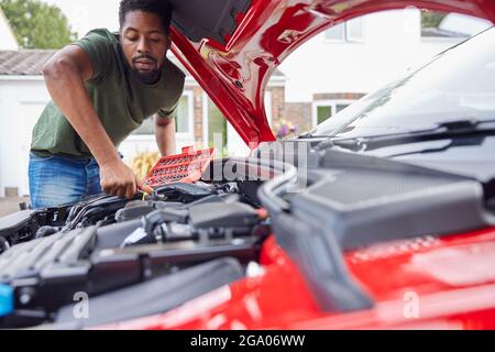 Homme travaillant sous le capot d'une voiture fixant le moteur à l'aide d'une clé Banque D'Images