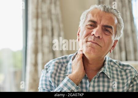 Homme mature à la maison souffrant de douleurs musculaires ou de douleurs dans le cou Banque D'Images