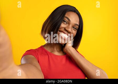 Afro-américain Blogger Lady faisant Selfie posant sur fond jaune Banque D'Images