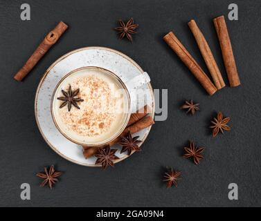 Thé au masala avec épices et lait. Boisson chaude indienne sur fond de pierre sombre. Vue de dessus, plan d'appartement. Banque D'Images
