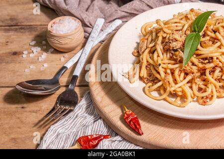 Plat traditionnel de pâtes siciliennes d'aubergines sautées nappées de sauce tomate. Plats servis sur une plaque de céramique, cuisine italienne, lumière dure moderne, sombre Banque D'Images