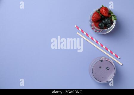 Smoothie aux myrtilles, ingrédients et pailles sur fond violet. Smoothie aux myrtilles frais avec ingrédients et pailles à boire sur violet Banque D'Images