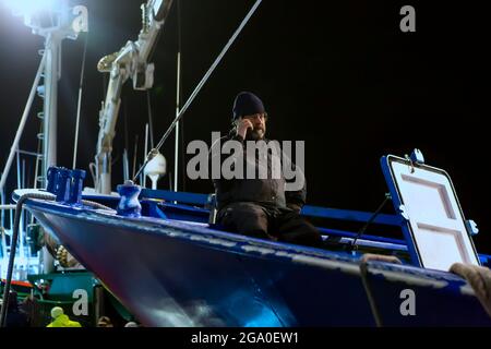 03-27-2019. Santoña, Cantabrie, Espagne un pêcheur vient d'arriver au port en appelant au téléphone assis sur l'arc du bateau Banque D'Images