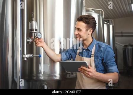 Travailleur, brasseur, propriétaire d'entreprise travaille à l'usine avec l'équipement, la technologie moderne Banque D'Images