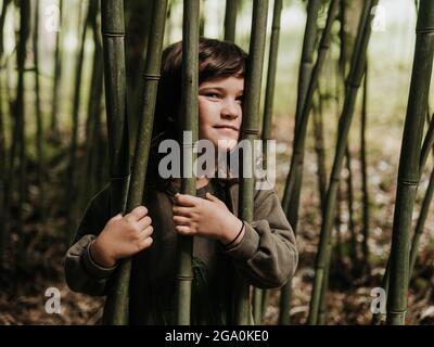 ENFANT SAUVAGE PARMI LE BAMBOU DANS LA NATURE Banque D'Images