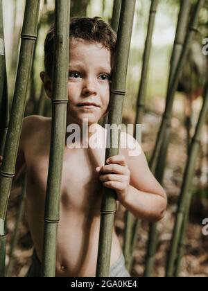 ENFANT SAUVAGE PARMI LE BAMBOU DANS LA NATURE Banque D'Images