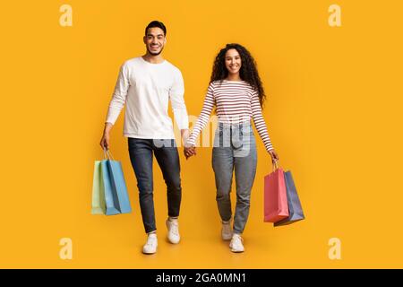 Portrait d'un heureux couple du Moyen-Orient marchant avec des sacs de shopping lumineux Banque D'Images