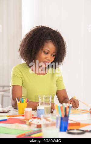 Portrait d'un professeur de cheveux bouclés d'une classe d'art aidant les élèves Banque D'Images