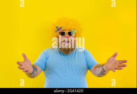 Gros homme émerveillé avec perruque dans la tête et lunettes de soleil Banque D'Images