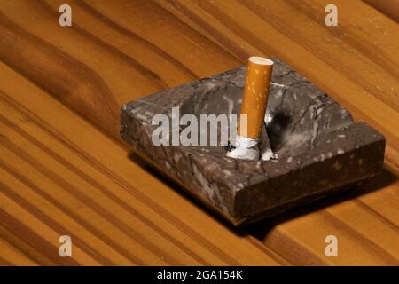 La cigarette s'éteint dans un cendrier en marbre sur une base en bois Banque D'Images