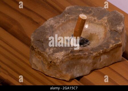 La cigarette s'éteint dans un cendrier en marbre sur une base en bois Banque D'Images
