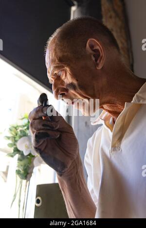 Peintre ou artiste mature ou senior avec crayon graphite devant l'appareil photo. Homme dans une chemise colorée à la peinture travaillant au studio Banque D'Images